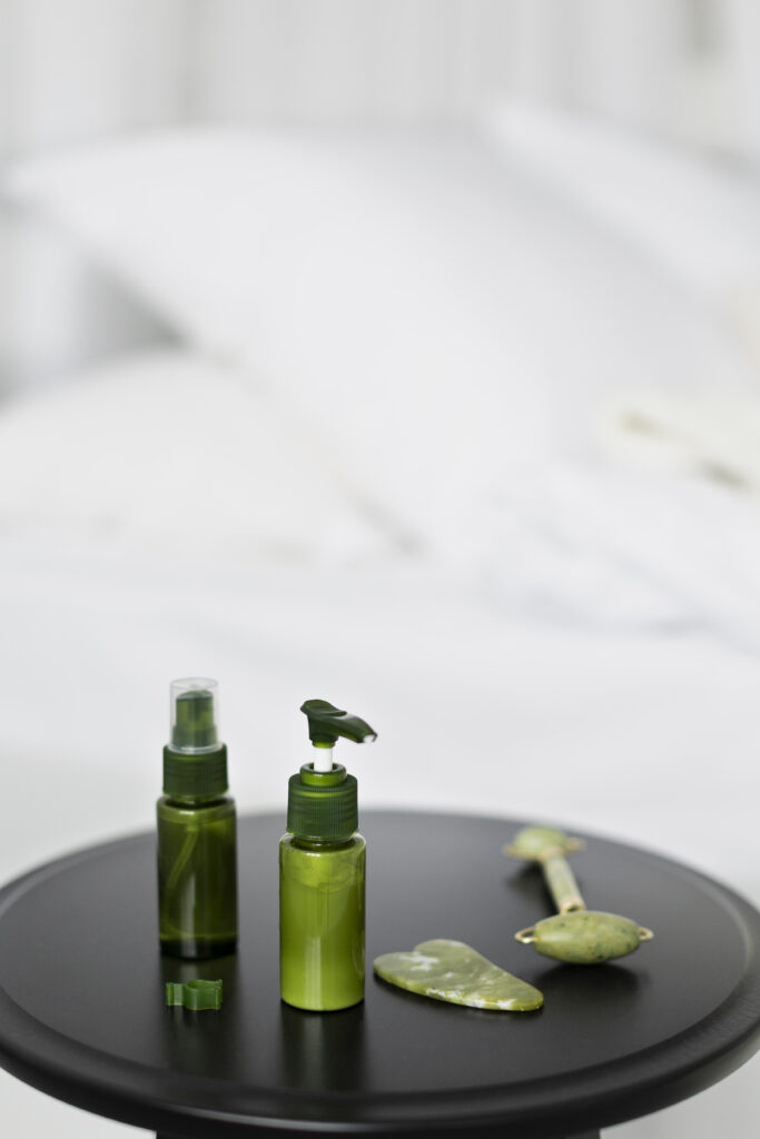 Kit de rutina facial con sérum y tónico en botellas verdes, acompañados de un rodillo de jade y gua sha para masaje del cutis.