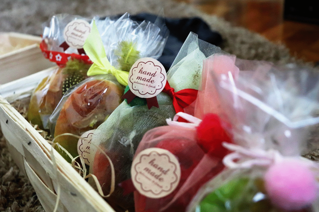 Cesta de madera con jabones artesanales envueltos individualmente en tul de colores con cintas, pompones y etiquetas redondas "hand made".