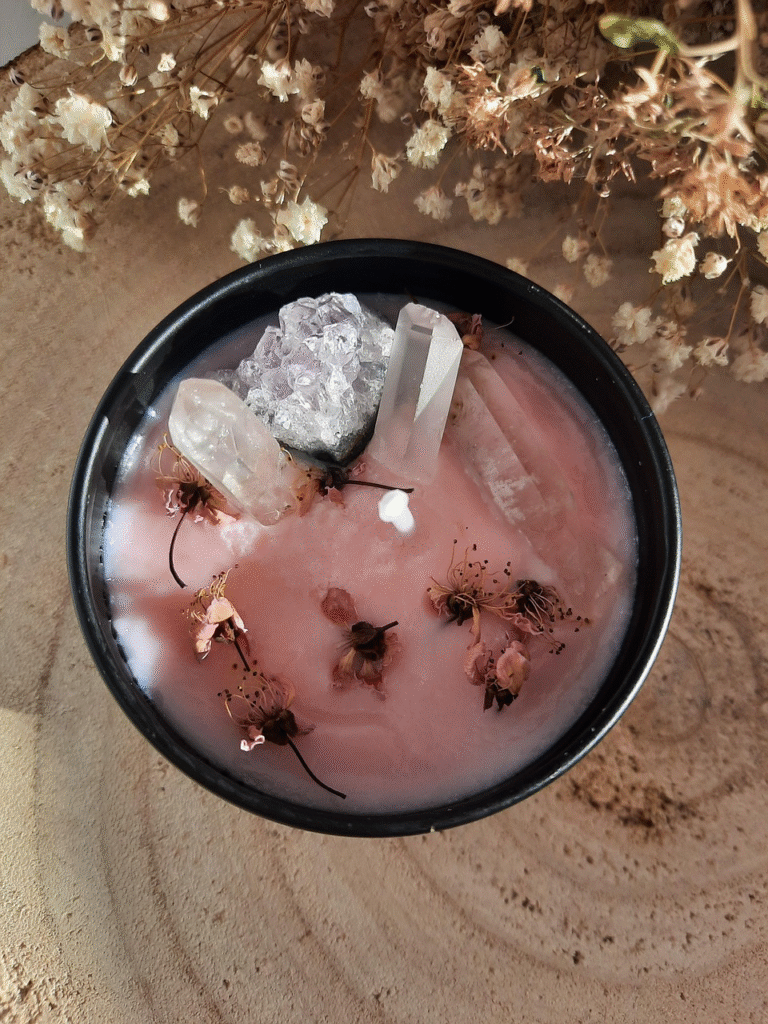 "Vela con cuarzos de cera de soya rosa en envase negro decorada con flores secas y puntas de cristal natural - Piñuela"