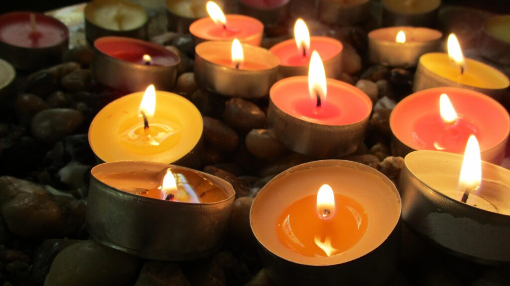 Grupo de velas aromáticas encendidas sobre piedras de río en un ambiente relajante con iluminación cálida.
